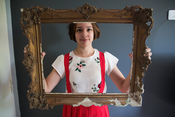 Chica sostiene un marco vintage para decoración en casa