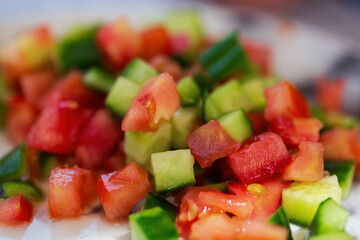 Close up of a pile of chopped vegetables. Salad with tomato and cucumber