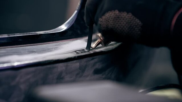 close-up At service station a mechanic solders a rubber gasket onto a metal part of the car