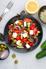 Greek salad on a light background. View from above. Composition of a plate of salad, olives and vegetables.