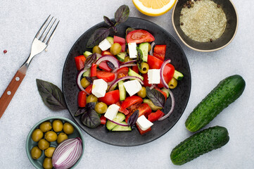Greek salad on a light background, horizontal. Top view. Composition from a plate of salad, olives and vegetables.