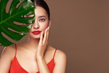 Close up woman face with green exotic leaf. Skin care beauty treatments concept. Model with clean,...