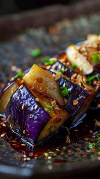 A closeup of delicate Japanese eggplant dish garnished with ginger and bonito flakes, emphasizing the glossy texture and rich color of the eggplant