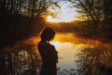 A young woman enjoy sunrise on the water.
