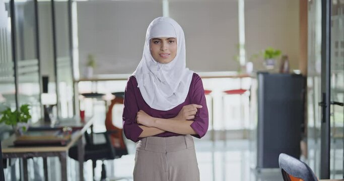 Indian smiling young adult gen z expert woman agent lady wear hijab standing proud cross hands look cam indoor job office day teen age boss girl staff owner fold arm do pose head shot video work place