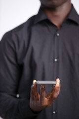 Black man in black long sleeves shirt holding mobile phone gacing camera frontal view, social media, news, entertainment
