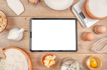 digital tablet and baking ingredients eggs on kitchen table worktop on background Baking bakery...