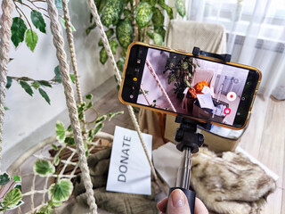 The blogger takes off stacks of clothes and signs with the words save, donate, throw away on cell phone. The concept of clutter, a debacle for a blog