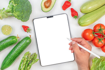 Male hand with variety of fresh vegetables working on digital tablet. organic healthy products....