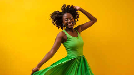 A young African woman energetically dances in a flowing green dress in front of a bright yellow background