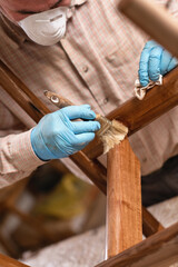 Carpenter protecting wooden chair with Polyurethane wood finish