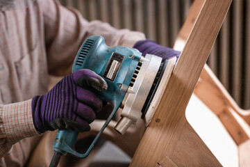 Carpenter hand using circular grinding machine in carpentry workshop