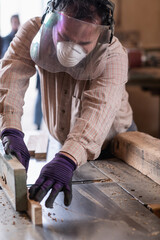 Carpenter woodworking, using thickness planer machine in carpentry workshop, wearing safety...