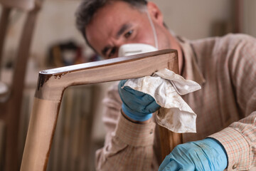 Process of applying oil-wax to wooden chair in carpentry workshop