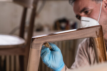 Carpenter applying lacquer to wooden furniture