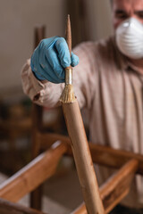 Carpenter wearing safety equipment applying clear wood stain on