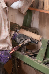 Woodworker shapes detail of a wooden chair with gouge in carpentry workshop