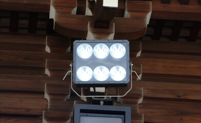 Large spotlight attached to brown wood wall is background. Beautifully shaped set in park to...