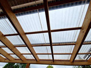 terrace with wooden pergola and plexiglass roof. vines are straining, crawling under the beams....