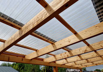 terrace with wooden pergola and plexiglass roof. vines are straining, crawling under the beams....