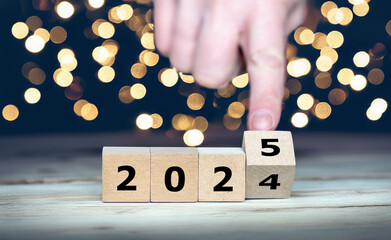 Hand turns wooden cube and changes the year 2024 to 2025. Symbol for the new year.