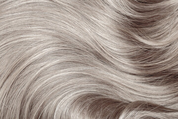 Blond hair close-up as a background. Women's long blonde hair. Beautifully styled wavy shiny curls....