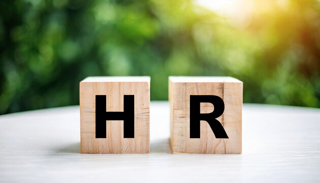 Two wooden blocks with the letters "HR" on a white table symbolize human resources, representing workforce management, recruitment, and employee relations in a professional or corporate setting