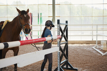 Side view of female jockey examining obstacle during training at ranch