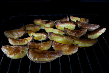 A large slice of country style potato on a hot barbecue on a charcoal grill. Delicious appetizers for an outdoor barbecue party.
