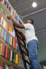 Student studying literature in a university library, surrounded by bookshelves, focused on gaining...