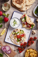 Gyros flatbread filled with chicken meat, tzatziki sauce and vegetables. Top view