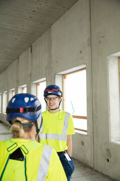 Smiling female civil engineers discussing while standing at construction site