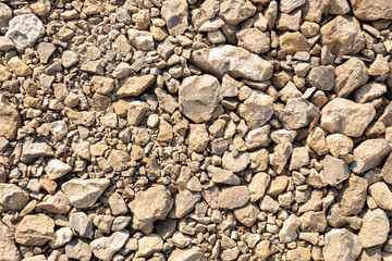 Different sized beige stones and gravel of different sizes and shades covering the ground. material...