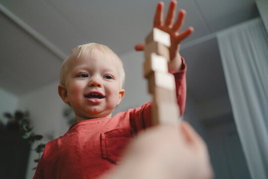 Low angle view of smiling cute boy stacking blocks at home