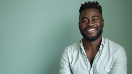 Obraz premium a smiling handsome black businessman wearing a shirt, feeling confident, isolated on a light green background.