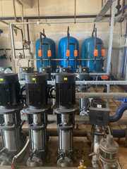 Interior of an industrial boiler room with pumps, many pipes, valves and sensors