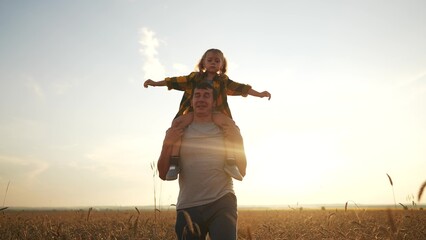 the child sits on father shoulders. happy life and family for child concept. a little girl spreads...