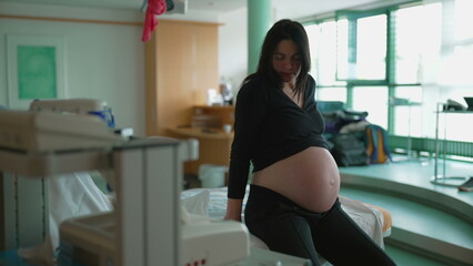 Pregnant Woman Struggling with Contractions, Seated by Hospital Bed During Labor, 30s Expecting...