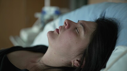 Suffering pregnant woman laid at hospital bed feeling contractions, close-up face of female patient with eyes closed struggles with pain during prelabor