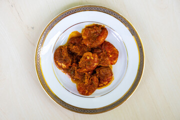 Delicious Bengali food chingri bhuna served on a white plate. Chingri vuna or prawn fish curry is a Bangladeshi-style dish with spicy gravy. Top view.