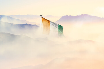 Ivory Coast  flag disappears in beautiful clouds with fog.