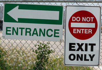 signs on a chain link fence (entrance) and do not enter, exit only