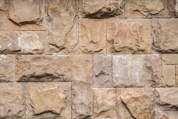 Solid house stone wall of roughly hewn stone closeup as stone background