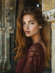 Obraz premium A woman with long brown hair and a red dress stands in front of a stone pillar. She has a pale complexion and a bright smile. Concept of confidence and beauty