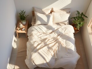 A bed with a white comforter and pillows, and a potted plant on the nightstand