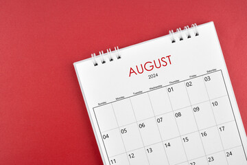 August 2024 desk calendar on red background.