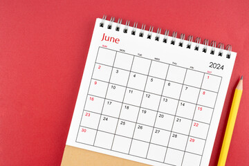 June 2024 desk calendar and pencil on red background.