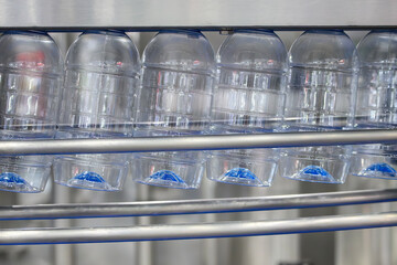 The  empty drinking water bottles  hanging on the conveyor belt for filling process.