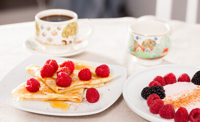 Breakfast of pancakes with fresh raspberries on table
