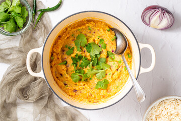 Top View of a Vegetable or Navratan Korma - Indian Mixed Vegetarian Curry in a Dutch Oven on a white surface. Real Food Photo